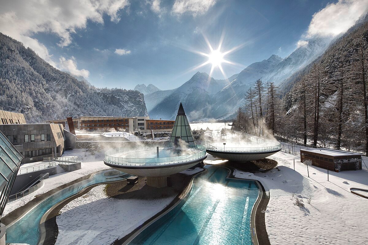 The three raised circular thermal pools of Aqua Dome in winter, steaming below the snow-covered Ötztal mountains.