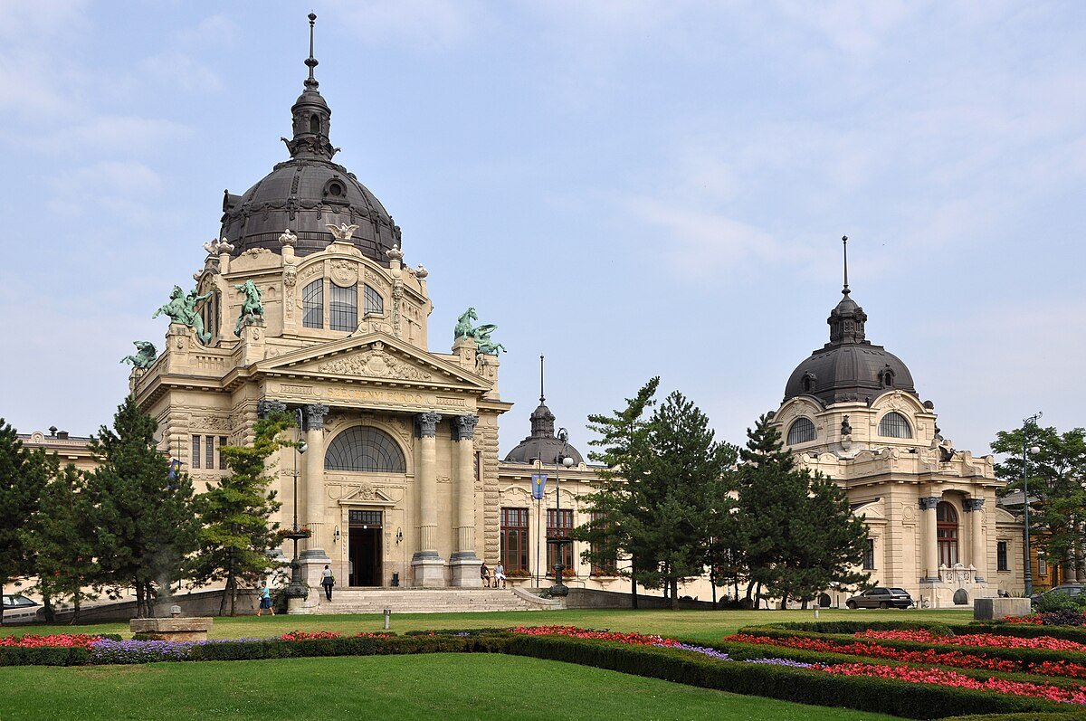 The neo-baroque main building and domes of Széchenyi Thermal Bath in Budapest, seen across its formal garden.
